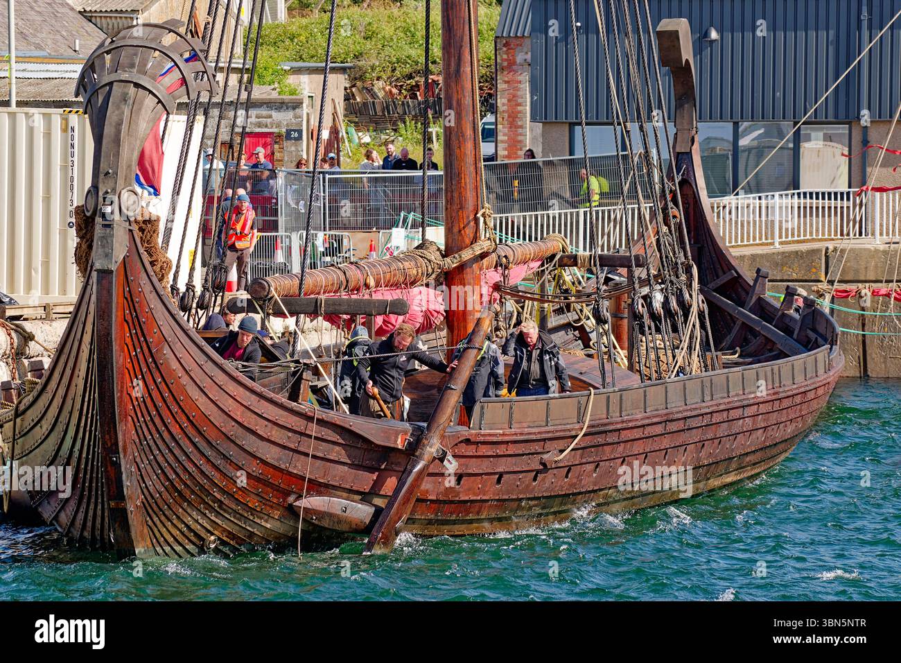 Navire viking le Draken Harald Harfagre plusieurs membres d'équipage qui fixent le gouvernail à Buckie Harbour Moray Scotland Banque D'Images