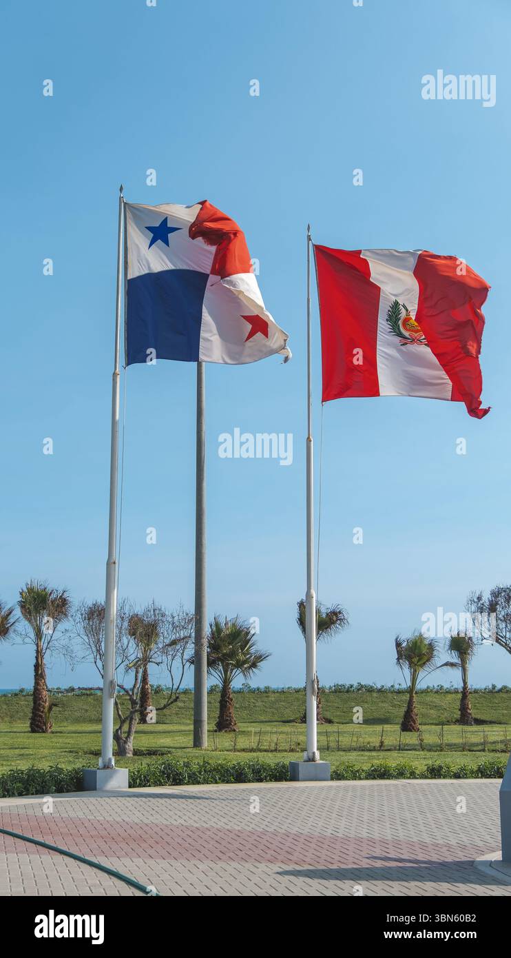 Drapeaux nationaux du panama et du pérou agitant au vent sur des mâts de drapeau par une journée ensoleillée Banque D'Images