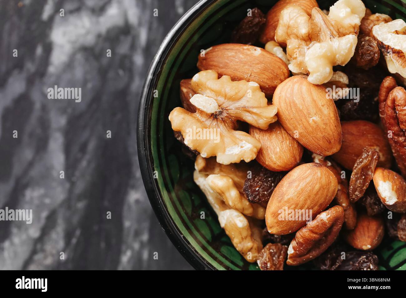 Noix mélangées dans un bol en céramique. Collation saine avec des amandes, des noix et des noisettes sur fond de marbre foncé. Aliment naturel riche en protéines. Gros plan. Banque D'Images