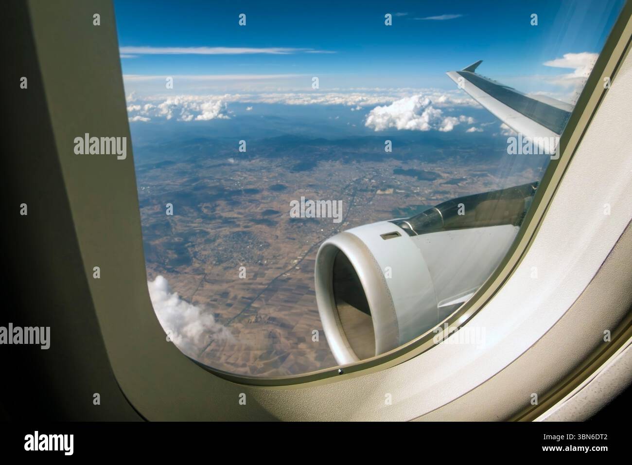 paysage, nuages, moteur et aile vus à travers la fenêtre de l'avion Banque D'Images