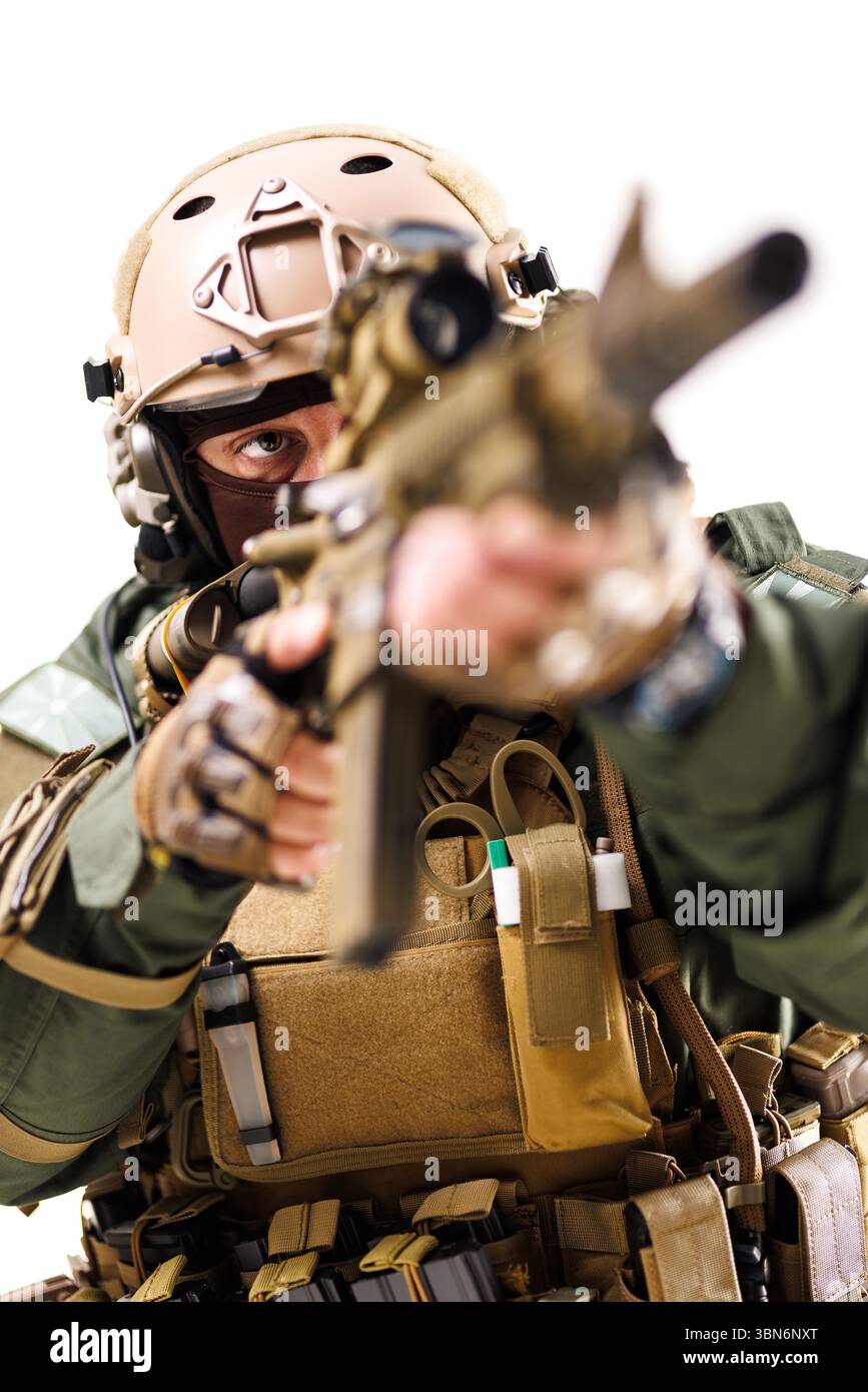 Un soldat tactique hautement équipé vise un fusil pendant une mission. La personne porte un équipement de protection, y compris un casque, des gants et un gilet, soulignez-le Banque D'Images