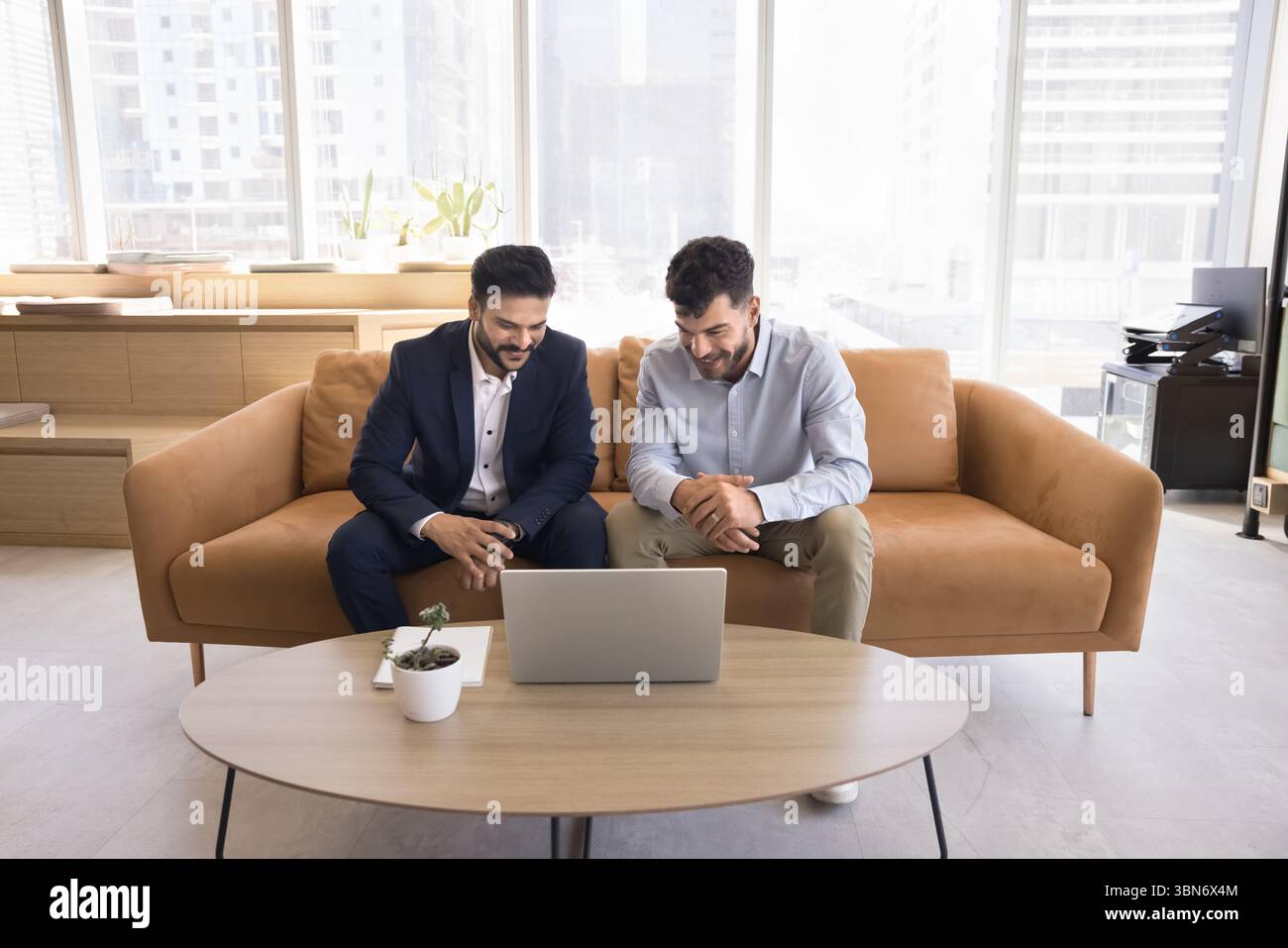 Deux jeunes hommes d'affaires heureux regardent la présentation vidéo sur l'écran d'ordinateur portable Banque D'Images