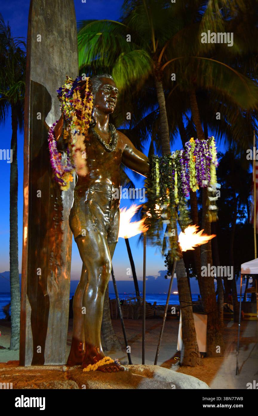 Une sculpture de la légende du surf Duke Kahanamoku est ornée de leis et entourée de torches à l'entrée de Banque D'Images