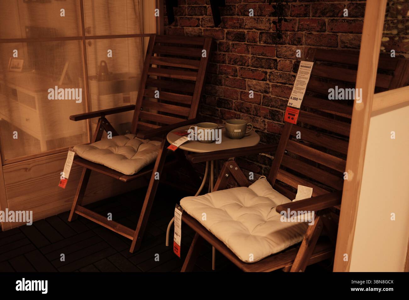 Des chaises de patio en bois avec des coussins de siège moelleux et une petite table ronde placée contre un mur de briques confortable créent un coin salon chaleureux et rustique dans un magasin à domicile Banque D'Images