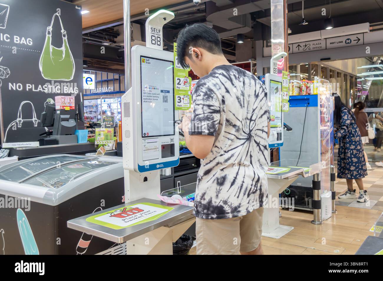 Big C supermarché, Bangkok, Thaïlande, Une personne utilise un kiosque de libre-service, scanner et payer, dans un magasin avec des panneaux « pas de sac en plastique ». Banque D'Images
