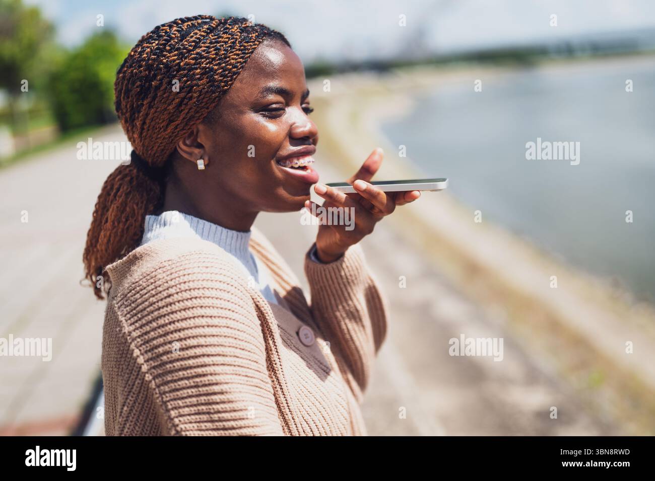 Une jeune femme noire parle au téléphone. Elle est heureuse et souriante. Banque D'Images