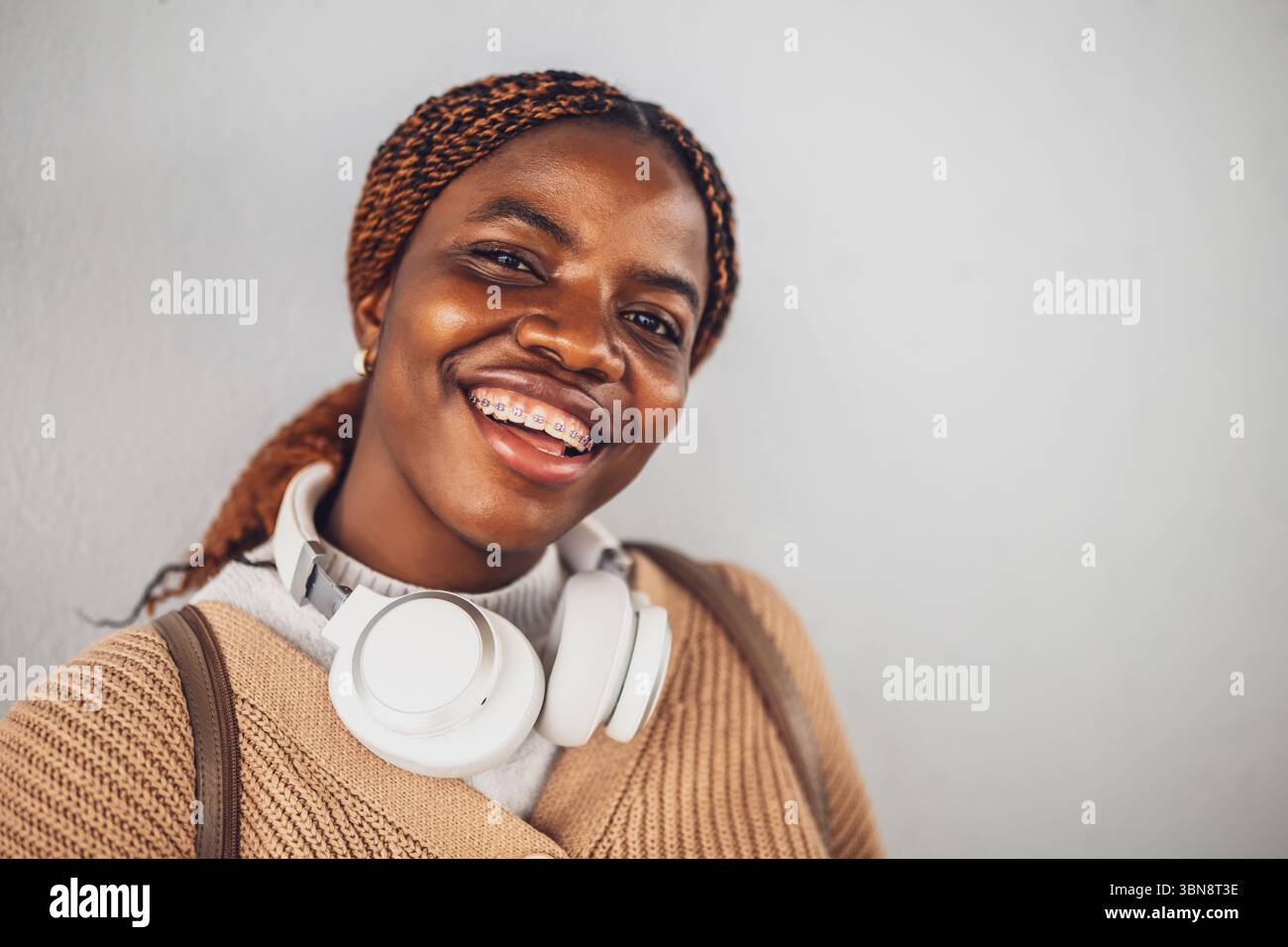 Portrait d'une jeune femme noire heureuse avec des appareils dentaires. Elle regarde la caméra et sourit. Banque D'Images