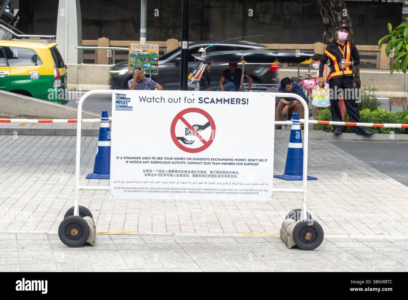 Un panneau en anglais « attention aux ESCROCS ! » est affiché sur une barrière roulante dans un espace public. Bangkok, Thaïlande, 'si un étranger demande à voir.. argent » Banque D'Images