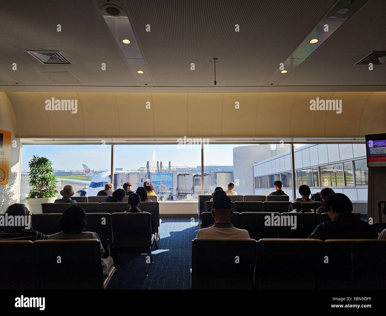 Salon d'attente de l'aéroport Tokyo Haneda avec passagers face au JAL Jet stationné Banque D'Images