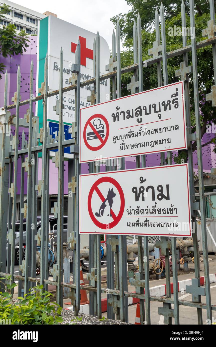 Un panneau thaïlandais sur une clôture métallique devant un bâtiment médical avec une croix rouge met en garde contre le tabagisme, la vapotage et les animaux de compagnie qui marchent. bangkok, Thaïlande Banque D'Images