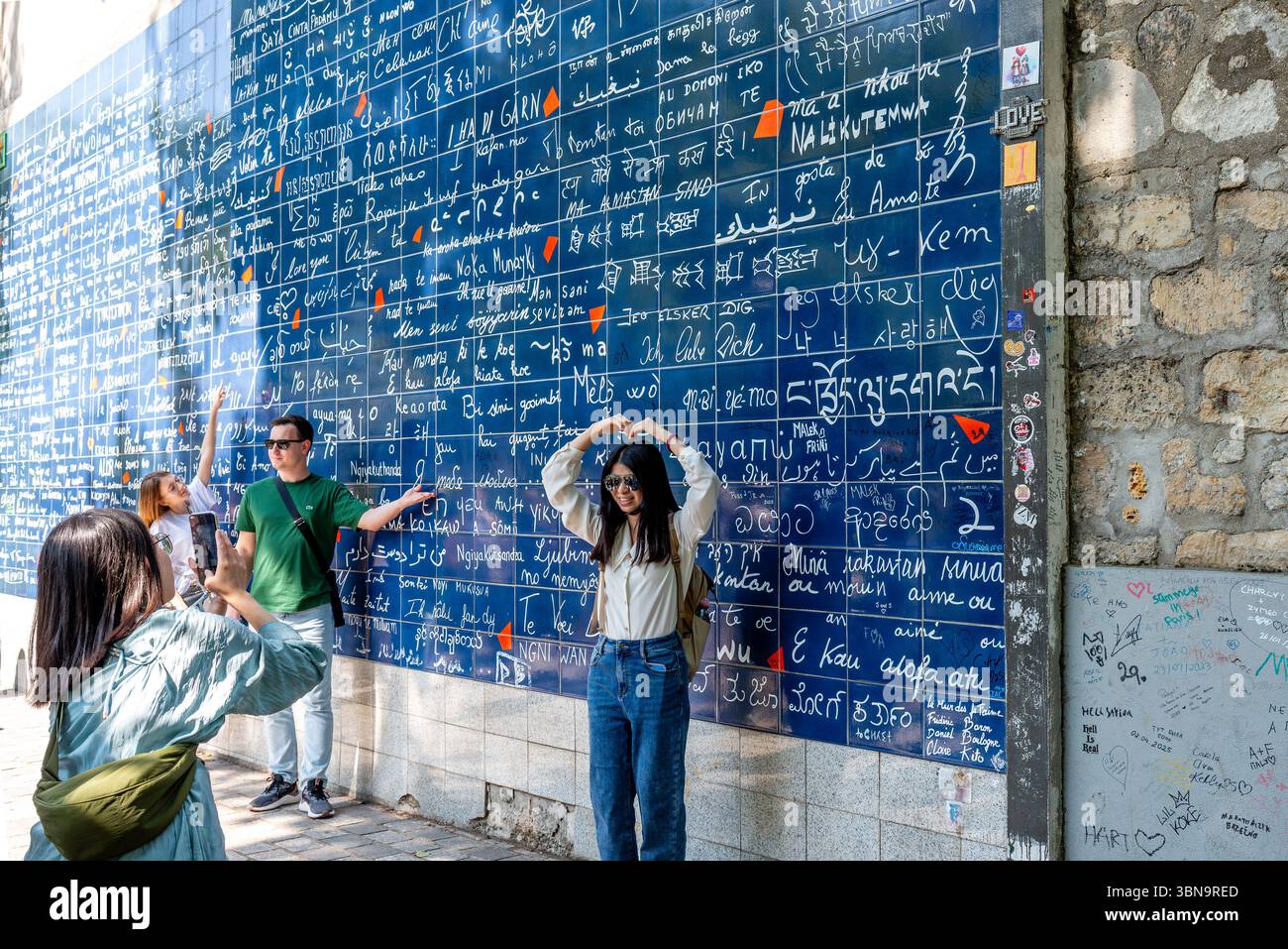 Touristes prenant des photos devant le mur de 'je t'aime' à Montmartre. Le mur figure également dans la série Netflix 'Emily in Paris' Banque D'Images