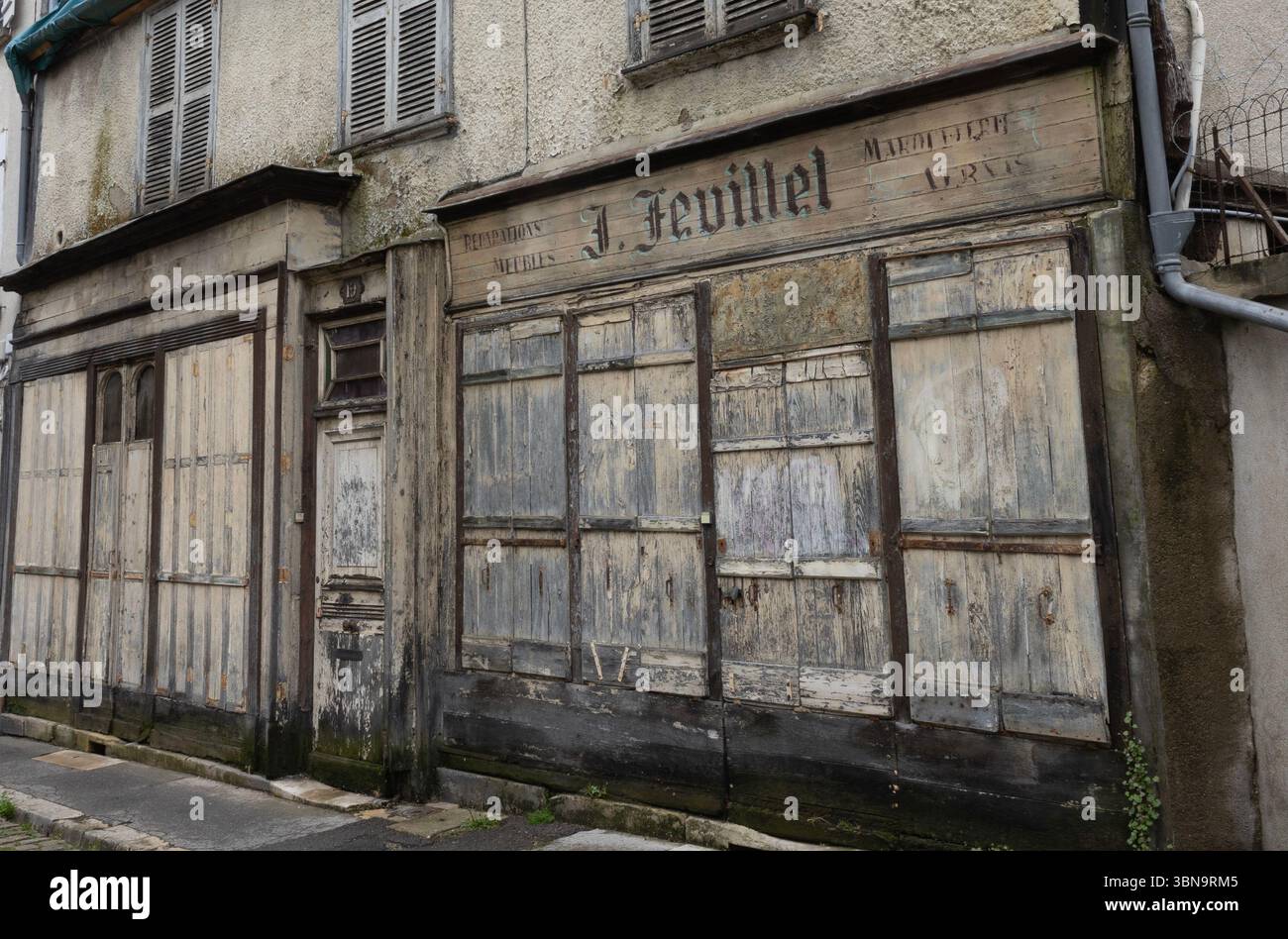 L'inscription sur cette ancienne façade de magasin de la rue de la porte jaune à Bourges, en France fermée depuis des années indique que J. feuillet a réparé des meubles. Banque D'Images