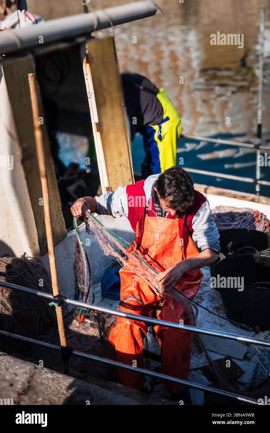 Pêcheurs espagnols qui s'occupent de leurs filets sur des bateaux de travail au port de Gandia, en Espagne Banque D'Images