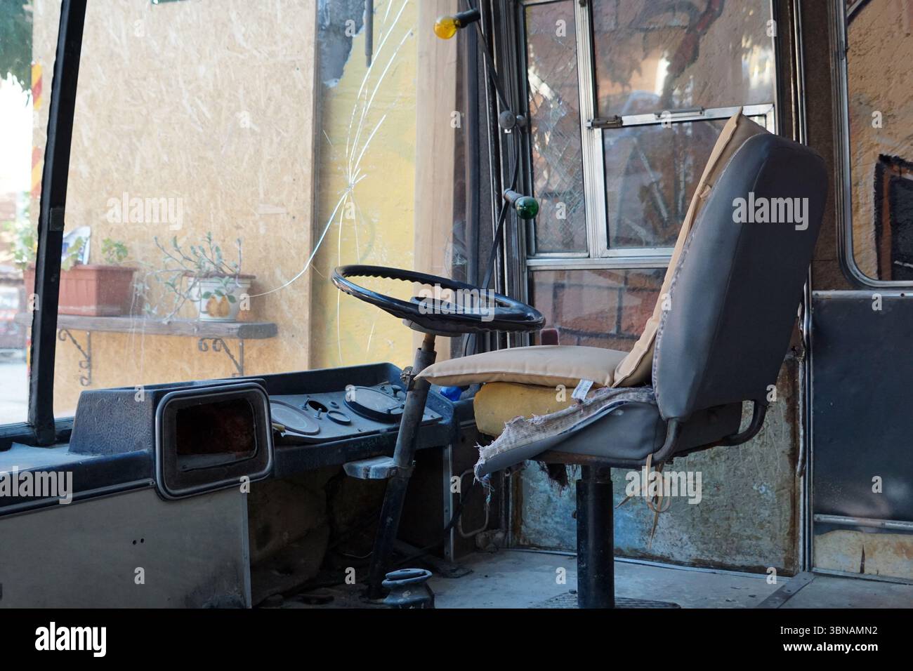 Nicosie (Lefkosia), Chypre, dernière capitale divisée du monde, l’image montre l’intérieur d’un vieux bus, probablement abandonné ou en mauvais état. L'intérieur du bus est dominé par un volant noir et un siège gris, qui semble être fait d'un tissu usé. Le siège est légèrement incliné vers la gauche. Le tableau de bord est visible, avec un volant noir et un panneau de commande avec différents boutons et cadrans. L'intérieur du bus est principalement composé de bois et de métal, avec une fenêtre qui est arborée. Le cadre de la fenêtre est en bois et en métal et la vitre est cassée. Le bus Banque D'Images