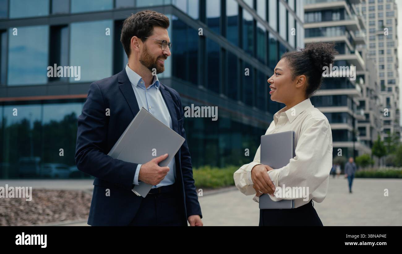 Deux gens d'affaires rencontrant câlin parlant dans la ville femme d'affaires afro-américaine femme heureuse souriante câlins avec homme d'affaires caucasien à l'extérieur Banque D'Images