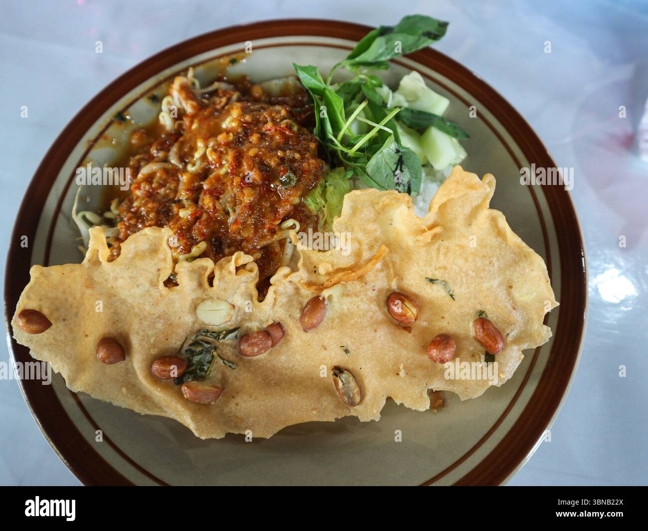 Il s’agit du pecel, un plat javanais traditionnel composé de légumes cuits à la vapeur mélangés garni d’une sauce épicée aux arachides, servi avec un rempeyek Banque D'Images