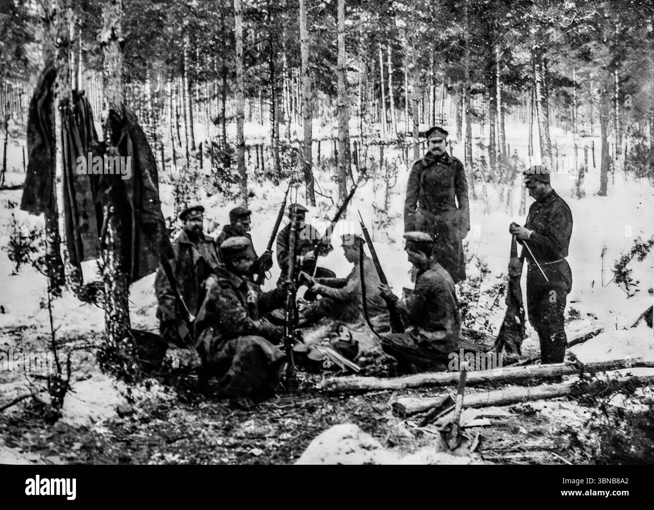 Soldats russes nettoyant leurs fusils à l'extérieur dans une forêt enneigée pendant la première Guerre mondiale. Malgré le froid, ils semblent à l'aise, assis sur des rondins et détendus comme dans une caserne. Photographiée par Pierre Choumoff, cette image capture la vie militaire quotidienne sur le front de l’est en hiver. Publié dans L’illustration, il révèle l’endurance et la routine des troupes russes dans des conditions difficiles Banque D'Images