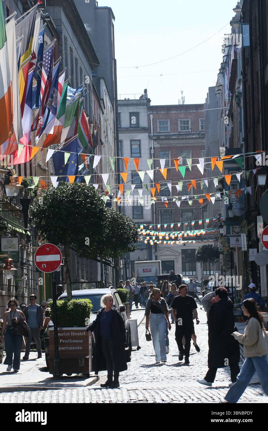 Dublin, Irlande - 8 avril 2025 - des banderoles vertes, blanches et oranges sur le thème irlandais et des drapeaux tricolores pendent au-dessus d'une rue de Temple Bar, dans le centre-ville de Dublin, par une journée ensoleillée Banque D'Images