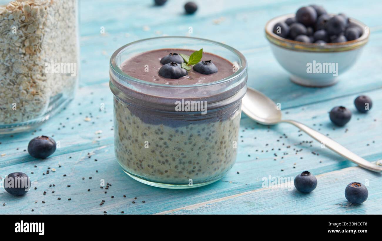 Avoine mélangée à de l'açaï et garnie de bleuets frais - un petit déjeuner fruité à base de plantes inspiré des superaliments brésiliens. Banque D'Images
