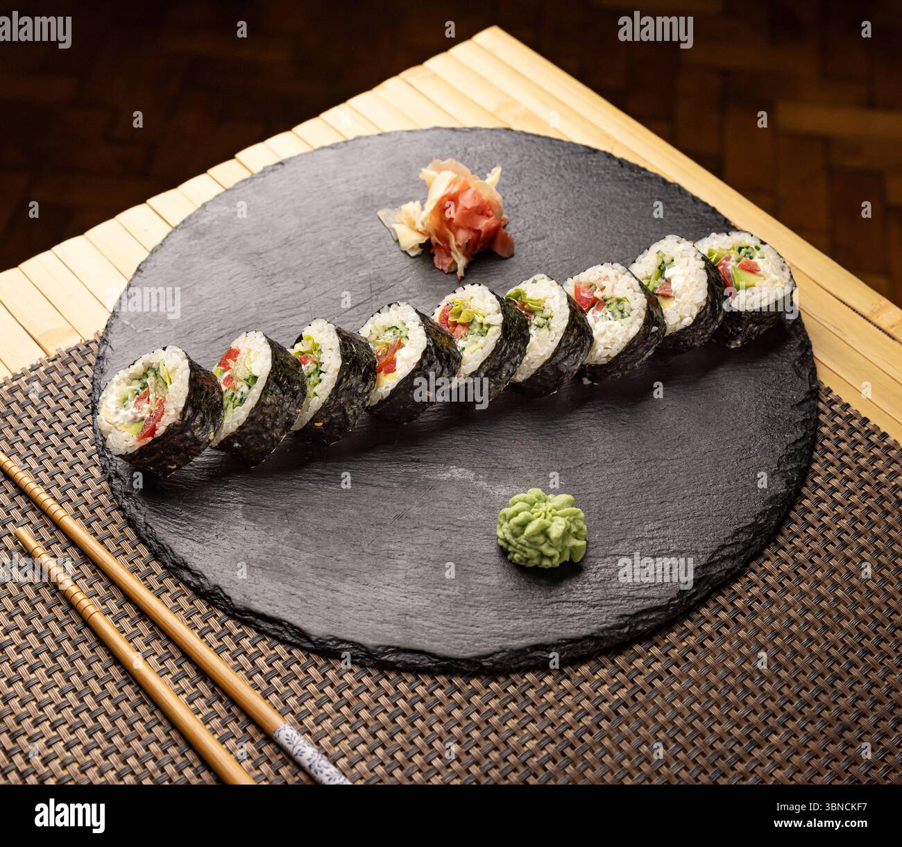 Délicieux rouleaux de sushi végétaliens avec des légumes couchés sur une assiette d'ardoise noire Banque D'Images