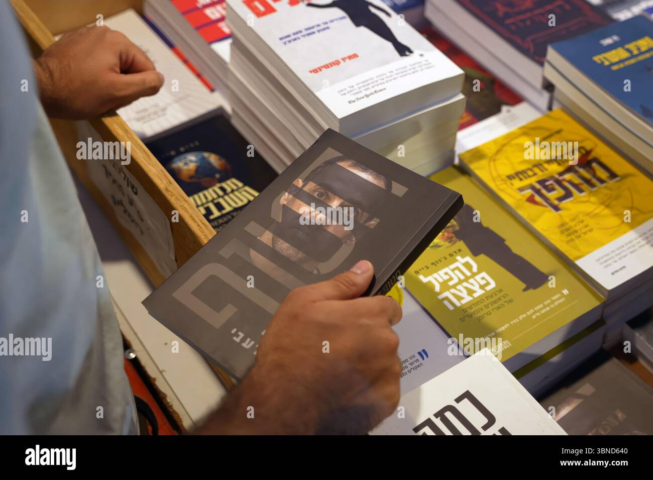 JÉRUSALEM - 1er JUILLET : une personne achète une copie de 'otage' écrit par Eli Sharabi, un otage israélien retourné qui détaille les 491 jours que Sharabi a été retenu captif à Gaza par le Hamas lors d'une foire du livre en plein air pendant la semaine du livre hébreu consacrée à la littérature hébraïque, le 1er juillet 2025 à Jérusalem. Israël Banque D'Images JÉRUSALEM - 1er JUILLET : une personne achète une copie de 'otage' écrit par Eli Sharabi, un otage israélien retourné qui détaille les 491 jours que Sharabi a été retenu captif à Gaza par le Hamas lors d'une foire du livre en plein air pendant la semaine du livre hébreu consacrée à la littérature hébraïque, le 1er juillet 2025 à Jérusalem. Israël Banque D'Images