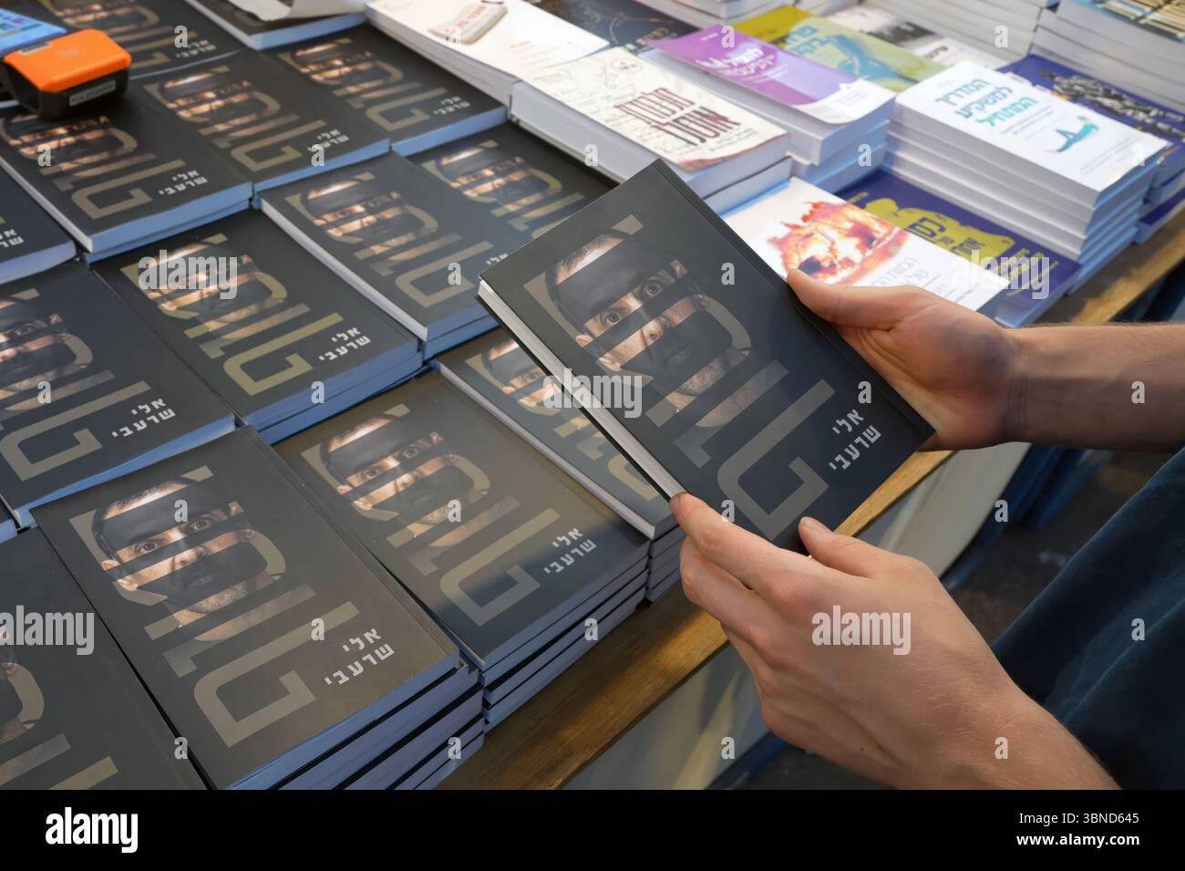 JÉRUSALEM - 1er JUILLET : une personne feuillette une copie de 'otage' écrit par Eli Sharabi, un otage israélien retourné qui détaille les 491 jours que Sharabi a été retenu captif à Gaza par le Hamas lors d'une foire du livre en plein air pendant la semaine du livre hébreu consacrée à la littérature hébraïque, le 1er juillet 2025 à Jérusalem. Israël Banque D'Images JÉRUSALEM - 1er JUILLET : une personne feuillette une copie de 'otage' écrit par Eli Sharabi, un otage israélien retourné qui détaille les 491 jours que Sharabi a été retenu captif à Gaza par le Hamas lors d'une foire du livre en plein air pendant la semaine du livre hébreu consacrée à la littérature hébraïque, le 1er juillet 2025 à Jérusalem. Israël Banque D'Images