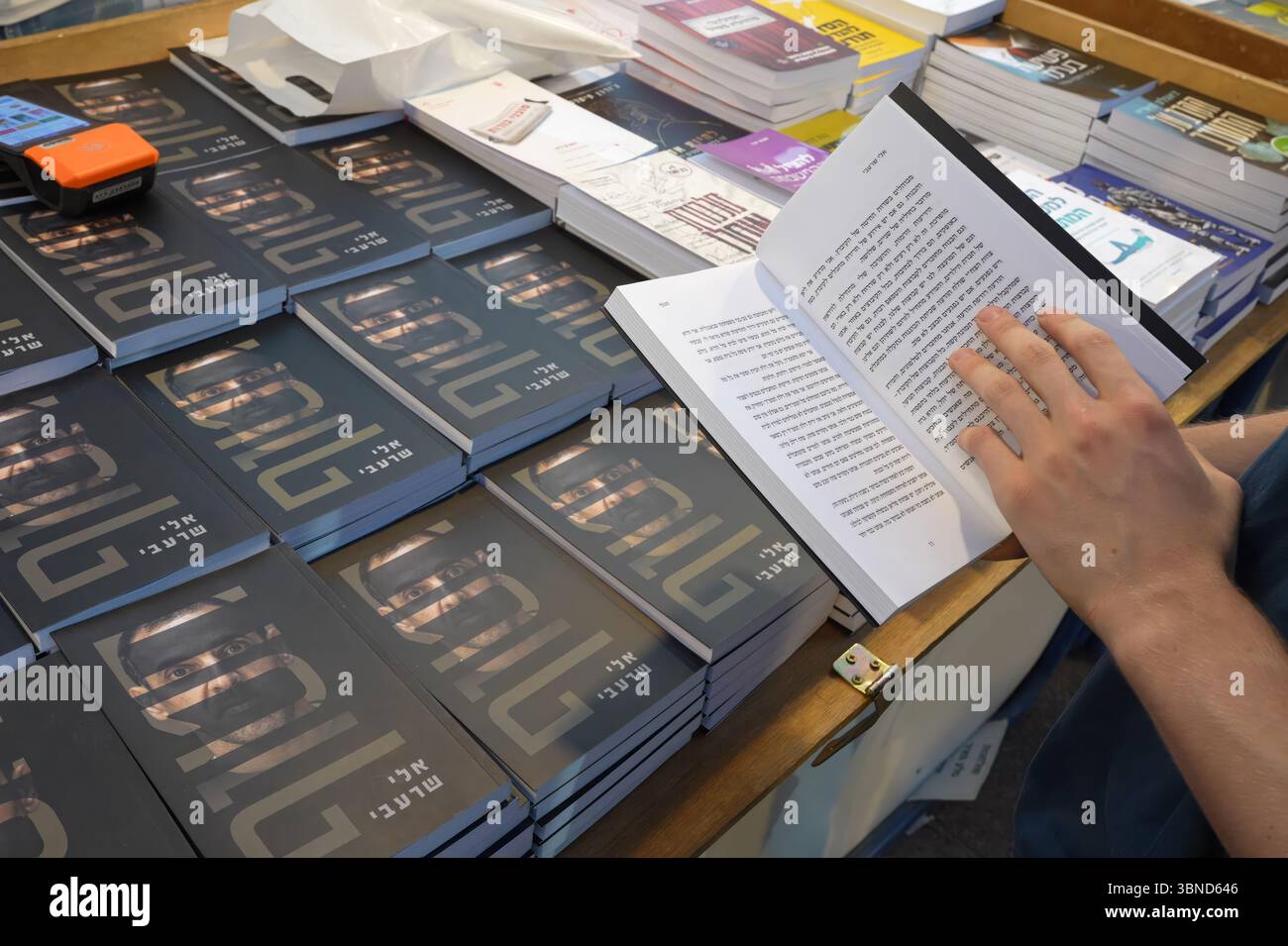 JÉRUSALEM - 1er JUILLET : une personne feuillette une copie de 'otage' écrit par Eli Sharabi, un otage israélien retourné qui détaille les 491 jours que Sharabi a été retenu captif à Gaza par le Hamas lors d'une foire du livre en plein air pendant la semaine du livre hébreu consacrée à la littérature hébraïque, le 1er juillet 2025 à Jérusalem. Israël Banque D'Images JÉRUSALEM - 1er JUILLET : une personne feuillette une copie de 'otage' écrit par Eli Sharabi, un otage israélien retourné qui détaille les 491 jours que Sharabi a été retenu captif à Gaza par le Hamas lors d'une foire du livre en plein air pendant la semaine du livre hébreu consacrée à la littérature hébraïque, le 1er juillet 2025 à Jérusalem. Israël Banque D'Images