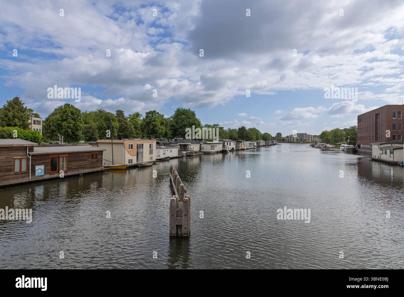 Une scène de canal tranquille à Gorinchem aux pays-Bas, avec de nombreuses péniches bordant les rives sous un beau ciel nuageux, offrant un gl unique Banque D'Images