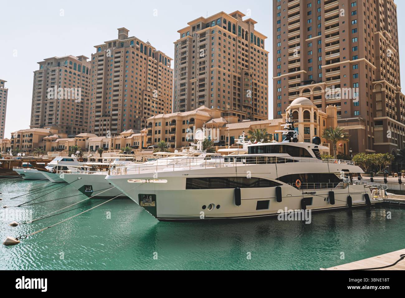 Porto Arabia Marina dans le coucher du soleil perlé montrant des yachts et des bateaux luxueux amarrés à la marina avec des bâtiments résidentiels en arrière-plan. Banque D'Images