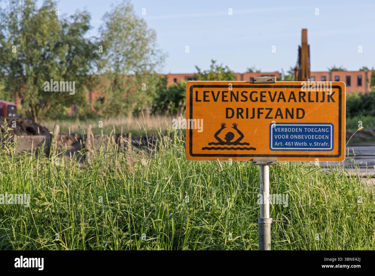 Un signe orange proéminent avertit pour drijfzand 'létal Quicksand' et interdit toute entrée non autorisée, debout au milieu d'herbes hautes dans un endroit potentiellement dangereux Banque D'Images
