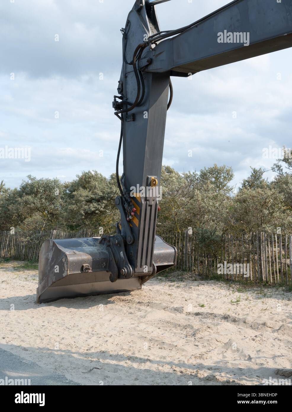 Une vue rapprochée détaillée montre un bras de pelle hydraulique méticuleusement préparé pour le processus d'excavation dans un environnement sablonneux Banque D'Images