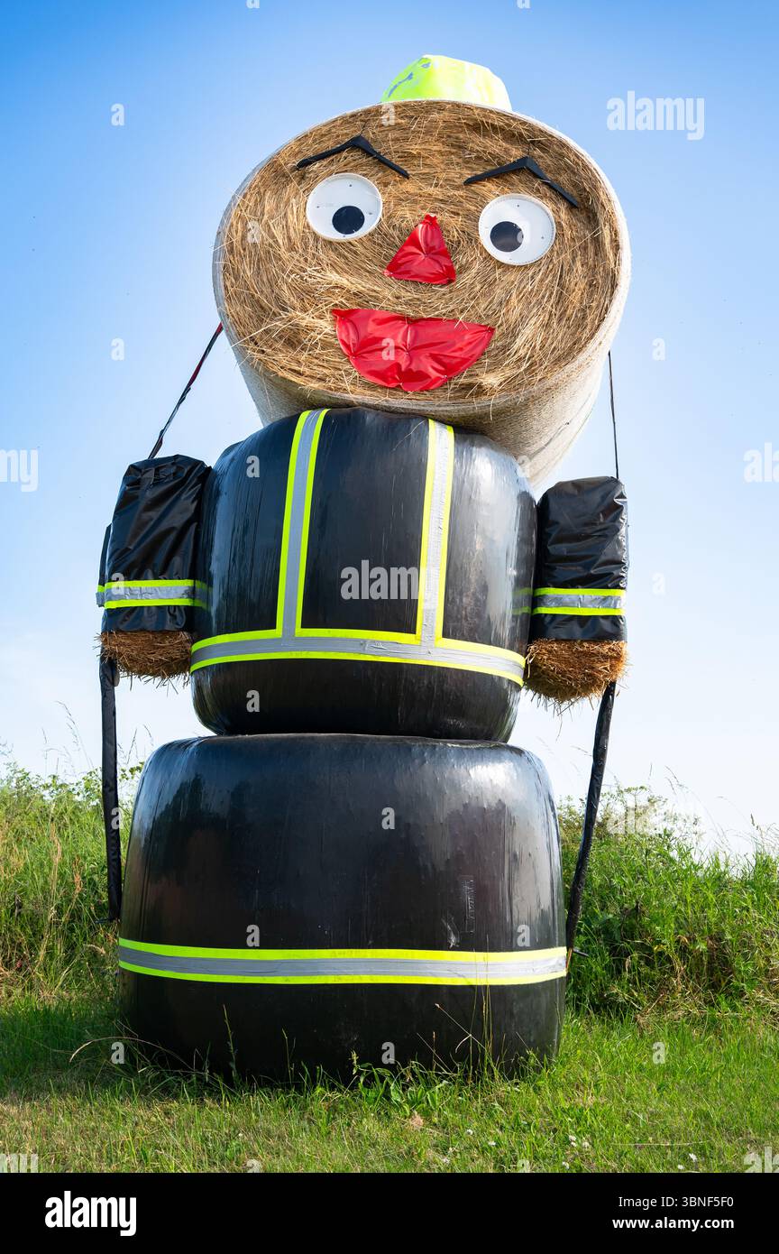 Énorme homme de paille, activité créative par les pompiers Osburg, Allemagne, tradition, balles avec collé sur le visage, habillé de feuilles de plastique noir et un chapeau Banque D'Images