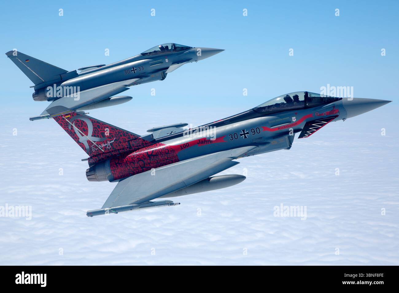 Deux avions Luftwaffe Eurofighter EF‑2000 Typhoon S, y compris le vol. 30+90 (série GS069) et 30+33 (série GS021), volent en formation au large de Wittmundhafen. Les deux sports centenaires de peintures commémoratives célébrant 100 ans de patrimoine unitaire. Les chasseurs canard-delta bimoteurs font preuve d'un positionnement en vol coordonné et d'une conception multirôle moderne. Banque D'Images