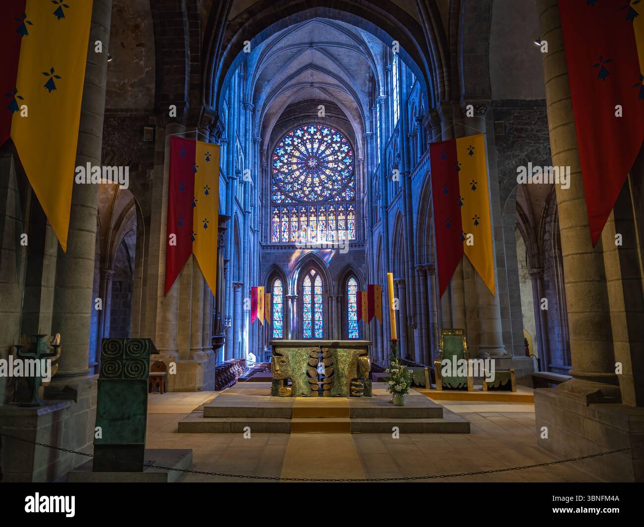 Autel contemporain en bronze d'Étienne Pirot dans la cathédrale Saint-Vincent de Saint-Malo, vu avec rosace, nef gothique et bannières liturgiques. Banque D'Images