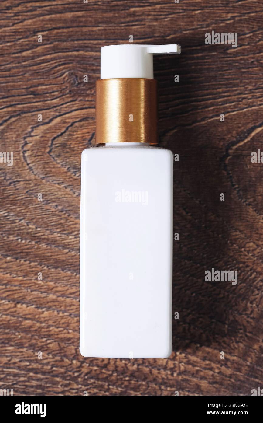 Flacon cosmétique blanc. Distributeur de pompe sur fond en bois. Nettoyer les produits de beauté pour la peau. Design d'emballage minimaliste. Hygiène et soin spa. Banque D'Images