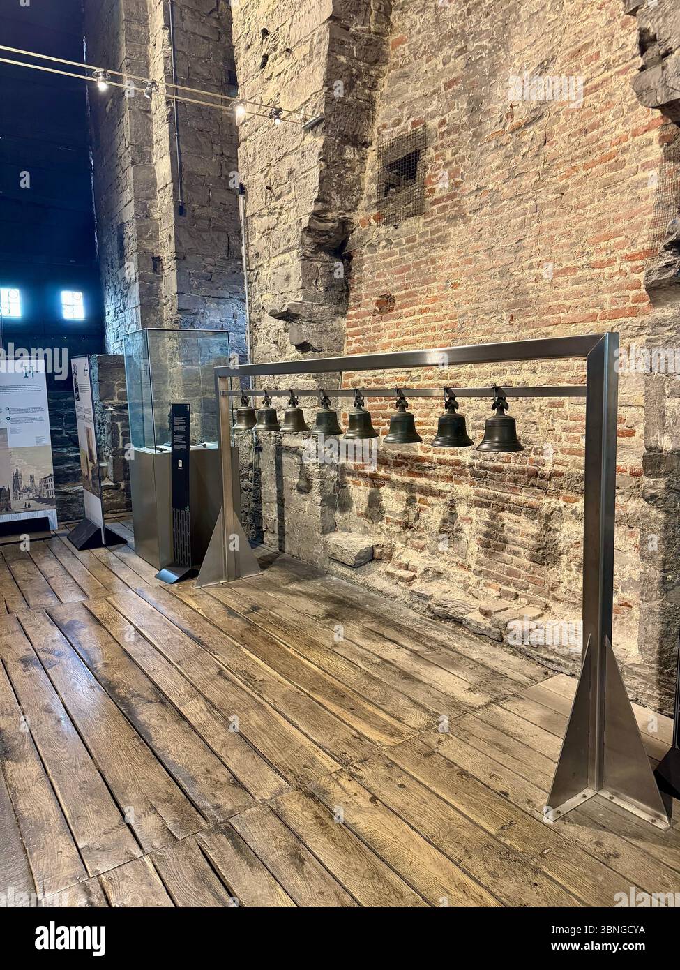 Rangée de cloches de tour historiques montées sur un cadre d'affichage en métal à l'intérieur du musée du Beffroi de Gand (Belfort van Gent), Belgique. - Image de stock capturée avec un smartphone