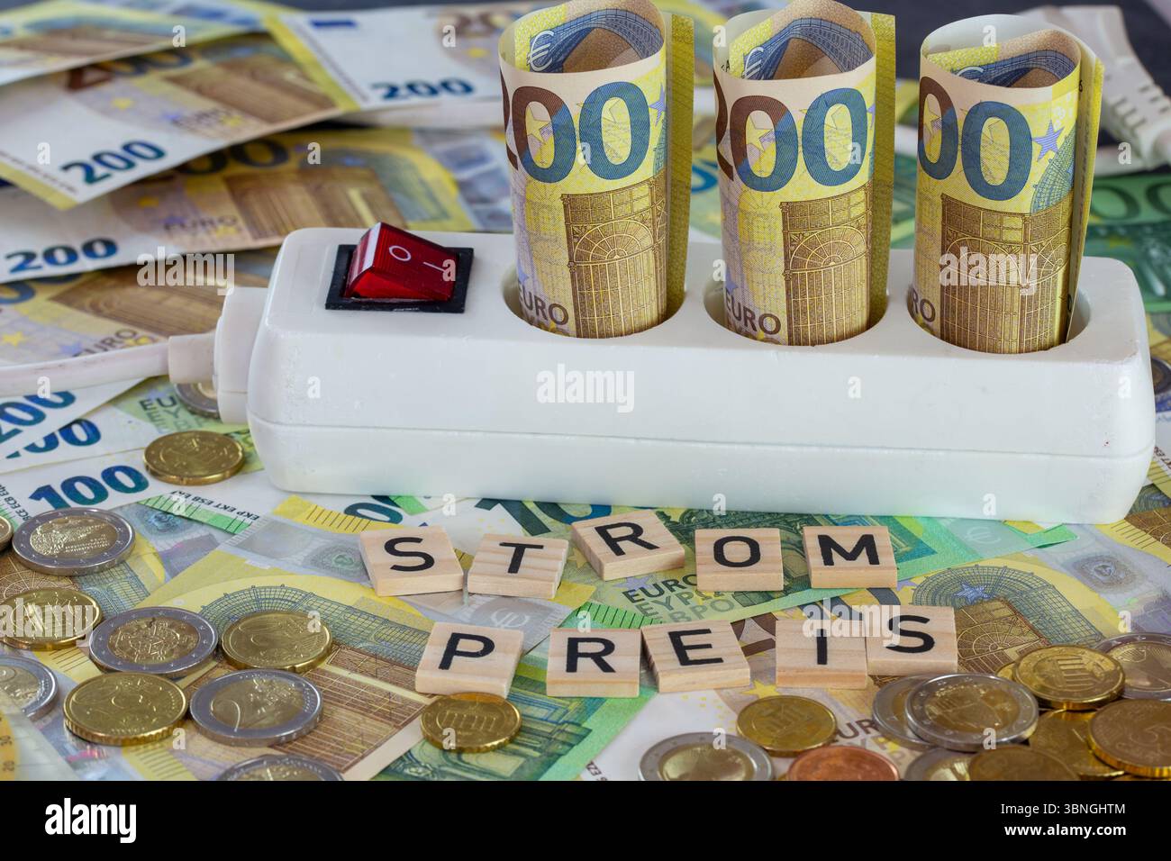 Image symbolique des coûts de l'électricité : prise multiple avec billets et pièces en euros, devant elle en lettres de bois le mot STROMPREIS Banque D'Images