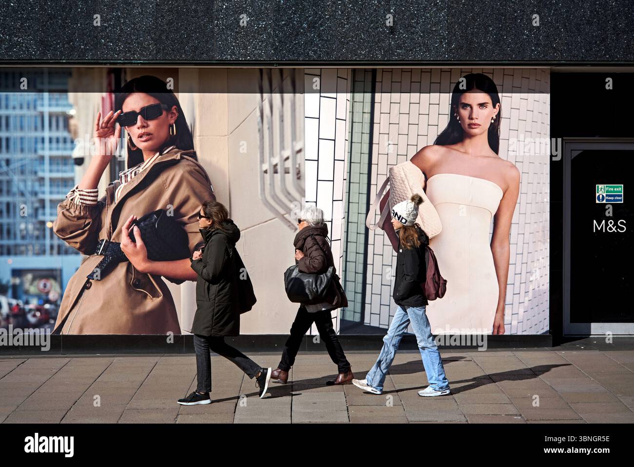 Trois jeunes femmes passant devant un magasin Marks & Spencer sur Princes Street, Édimbourg, Écosse, Royaume-Uni. Banque D'Images