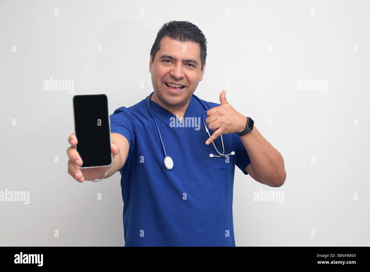 Un médecin latino-américain à la peau foncée avec un stéthoscope montre son téléphone portable pour avoir des consultations en ligne avec ses patients Banque D'Images Un médecin latino-américain à la peau foncée avec un stéthoscope montre son téléphone portable pour avoir des consultations en ligne avec ses patients Banque D'Images