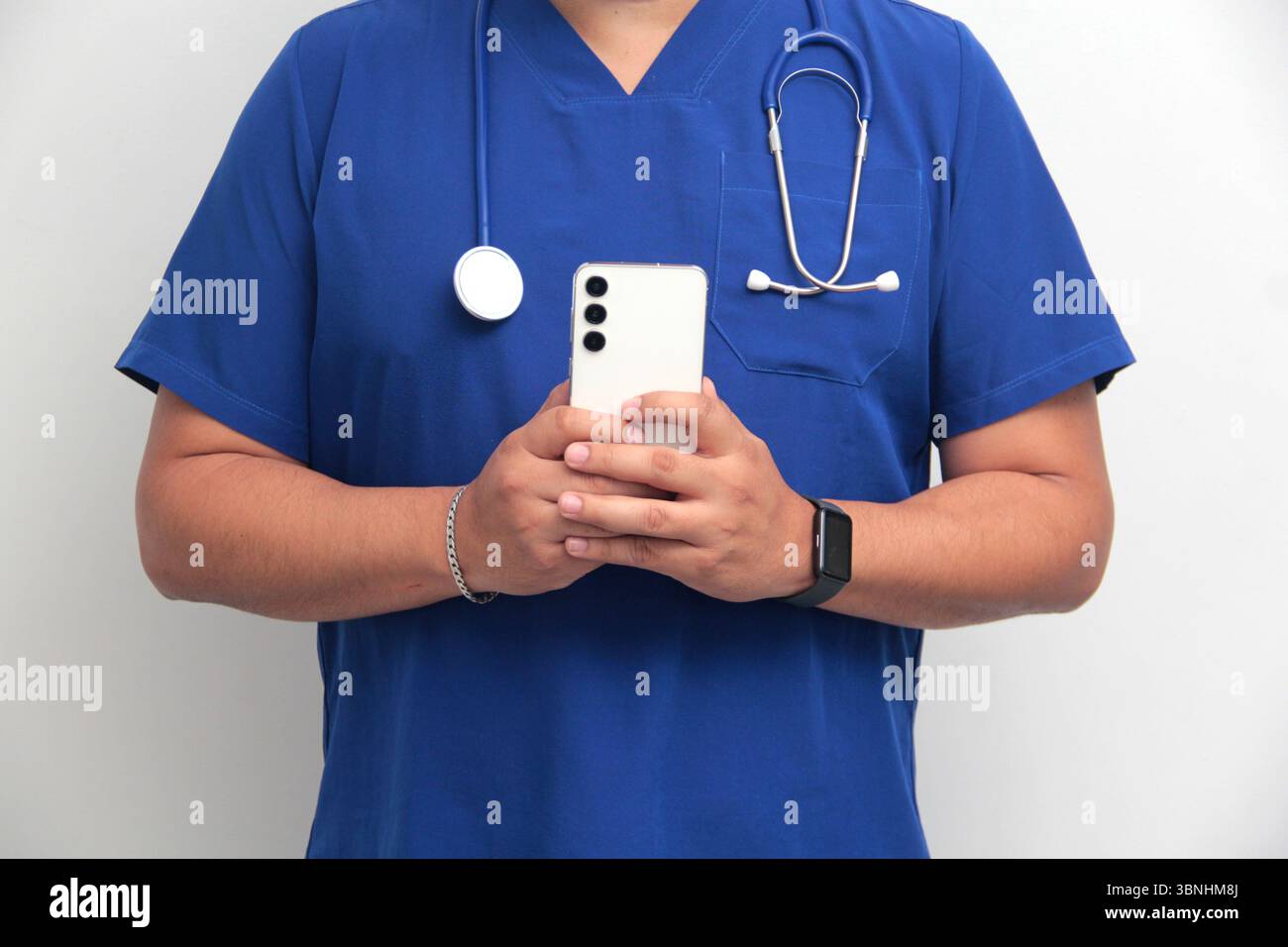 Un médecin latino-américain à la peau foncée avec un stéthoscope montre son téléphone portable pour avoir des consultations en ligne avec ses patients Banque D'Images Un médecin latino-américain à la peau foncée avec un stéthoscope montre son téléphone portable pour avoir des consultations en ligne avec ses patients Banque D'Images