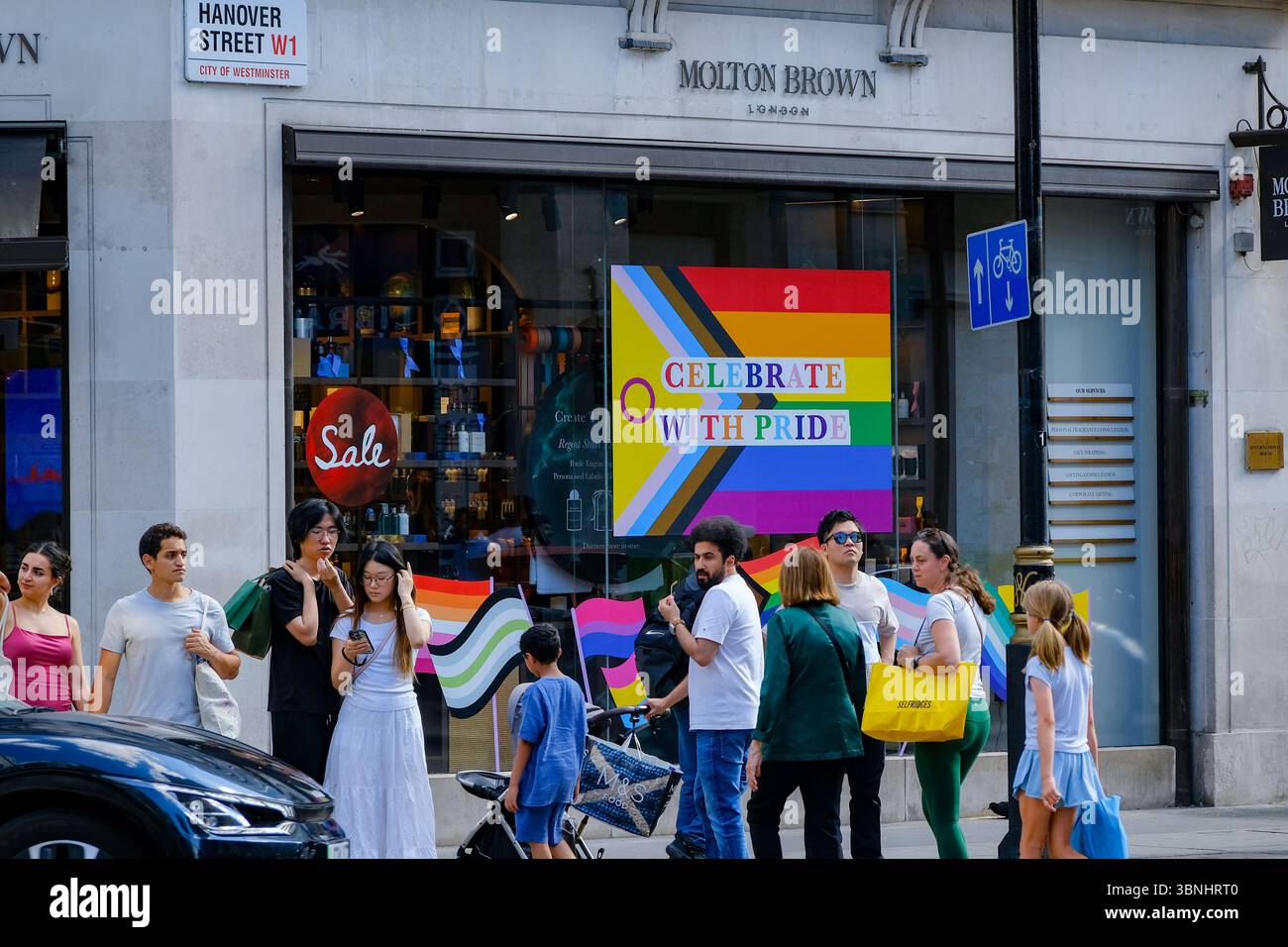 Les clients passent devant la vitrine du magasin Molton Brown avec un drapeau Pride affiché dans la vitrine disant : « célébrez avec fierté ». Banque D'Images