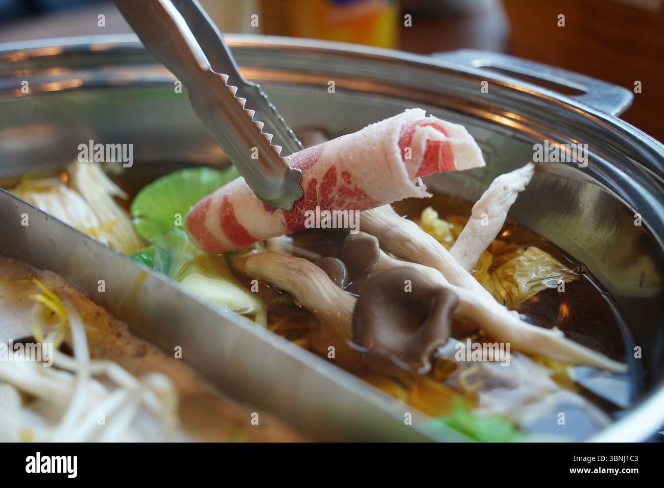 Hot pot avec de fines tranches de viande et des légumes frais – gros plan sur moment de cuisson Banque D'Images
