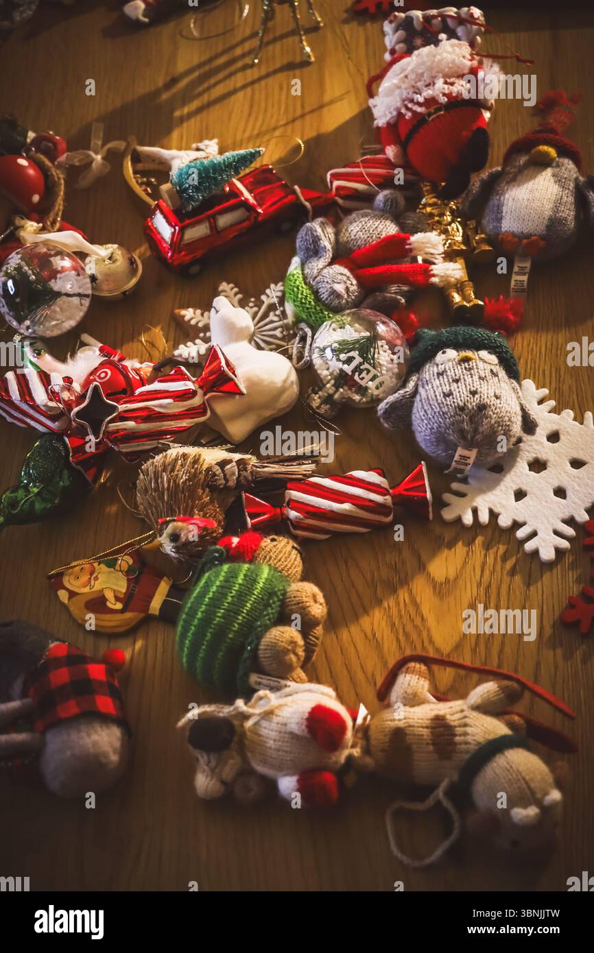 Une vue en grand angle d'une collection de divers ornements de Noël dispersés sur une table en bois. Pingouin tricoté et père Noël, boules en verre, flocon de neige en feutre Banque D'Images