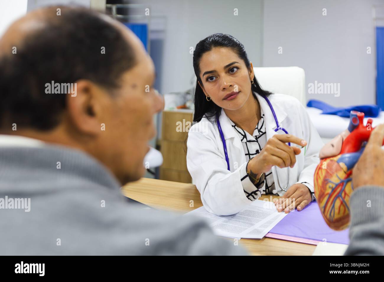 Une jeune femme médecin dispense des soins professionnels à un patient masculin âgé dans un hôpital latino-américain, favorisant un soutien et une compassion Banque D'Images