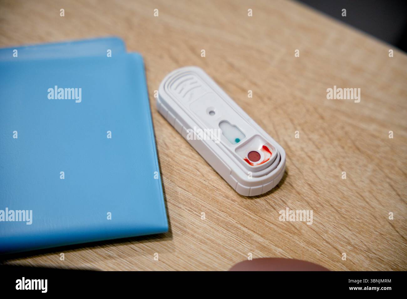 Kit de test rapide vétérinaire placé sur une surface en bois à côté d'un dossier bleu. Essentiel pour des diagnostics rapides dans la pratique vétérinaire, assurant le respect du temps Banque D'Images
