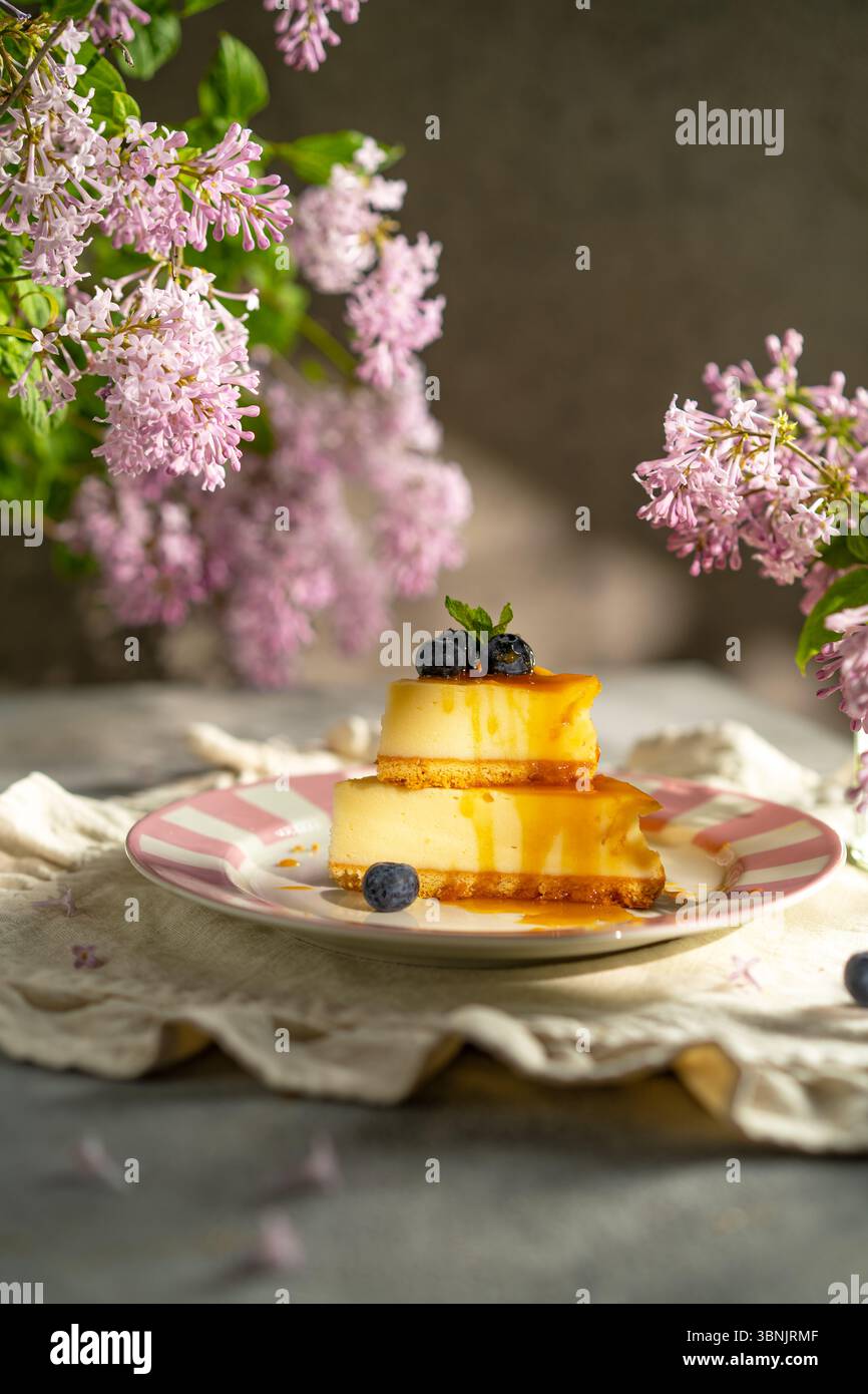 Un appétissant cheesecake arrosé de sauce caramel doré, garni de myrtilles fraîches, et servi sur une assiette décorative, entouré de delic Banque D'Images