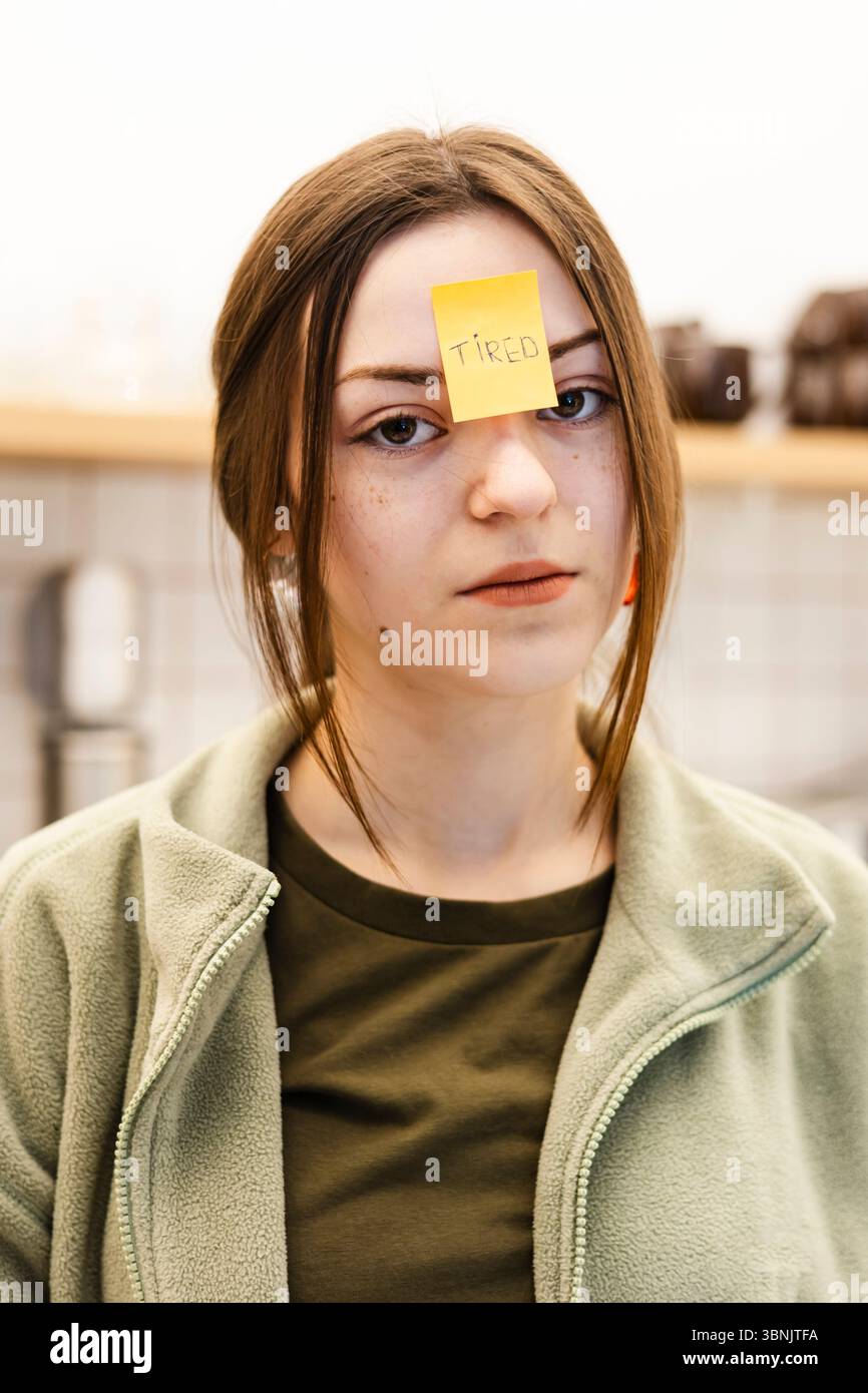 Un employé de café avec une note fatiguée sur le front, dépeignant la fatigue. Cette image capture un moment d'épuisement et d'expression dans un café confortable Banque D'Images