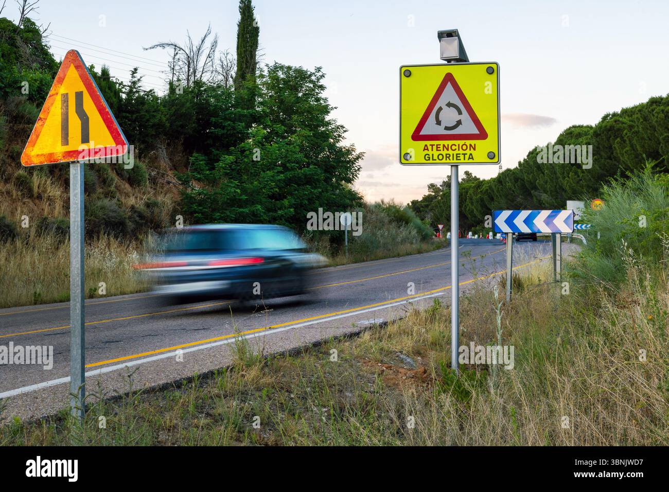 Une voiture roule le long d'une route rurale flanquée de feux de circulation, mettant en valeur d'importantes caractéristiques de sécurité routière et mettant l'accent sur la navigation prudente à travers chang Banque D'Images