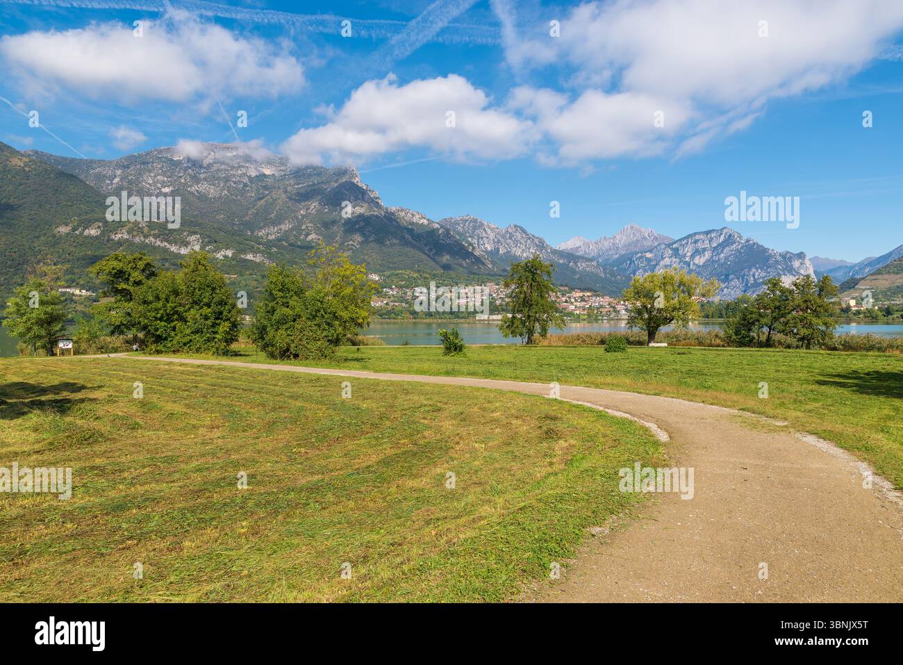 Sentier de terre à travers les prairies, sur les rives d'un lac par une journée ensoleillée claire. Lac Annone ou lac Oggiono, Italie. Piste cyclable pour piétons Banque D'Images