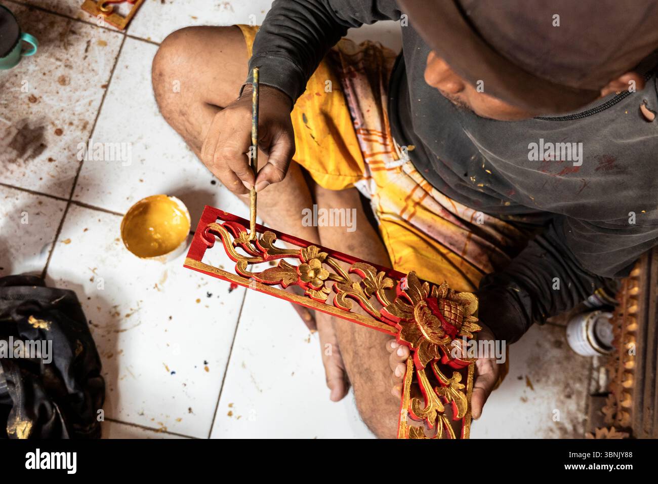 Un artisan peint méticuleusement des sculptures en bois complexes à Bali, mettant en valeur la riche tradition de l'artisanat dans la menuiserie et la peinture, reflétant Banque D'Images